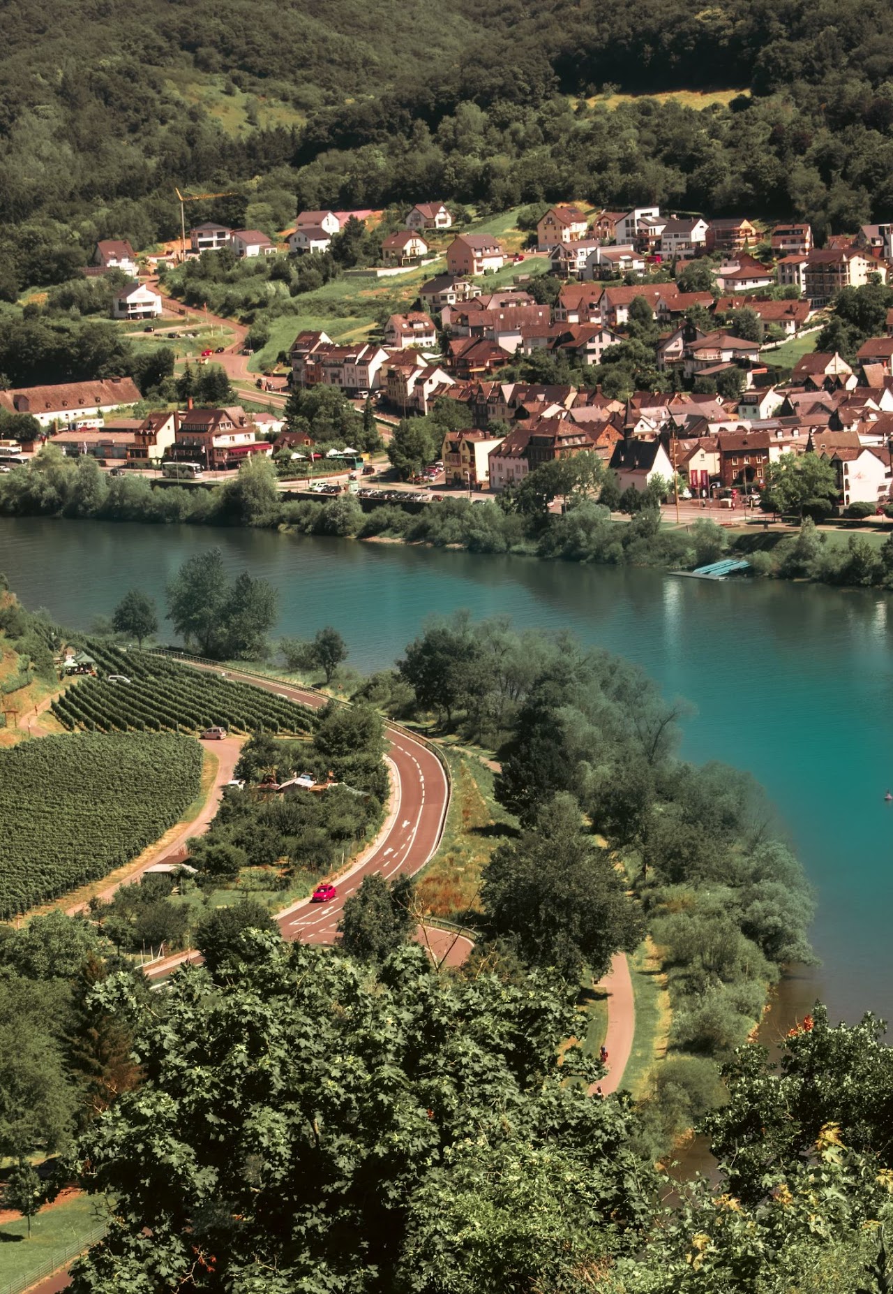 A riverside town with winding road, fields, and water.